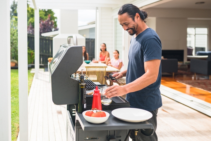 Man with smile on his face preparing dinner for family on bbq