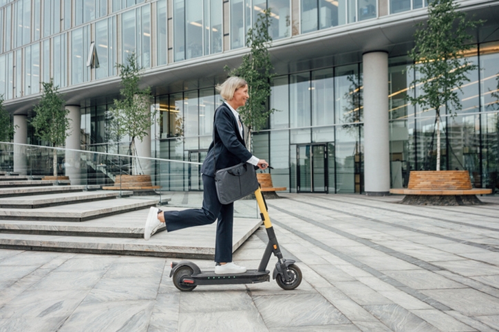 Business woman riding a electric push scooter to commute to work