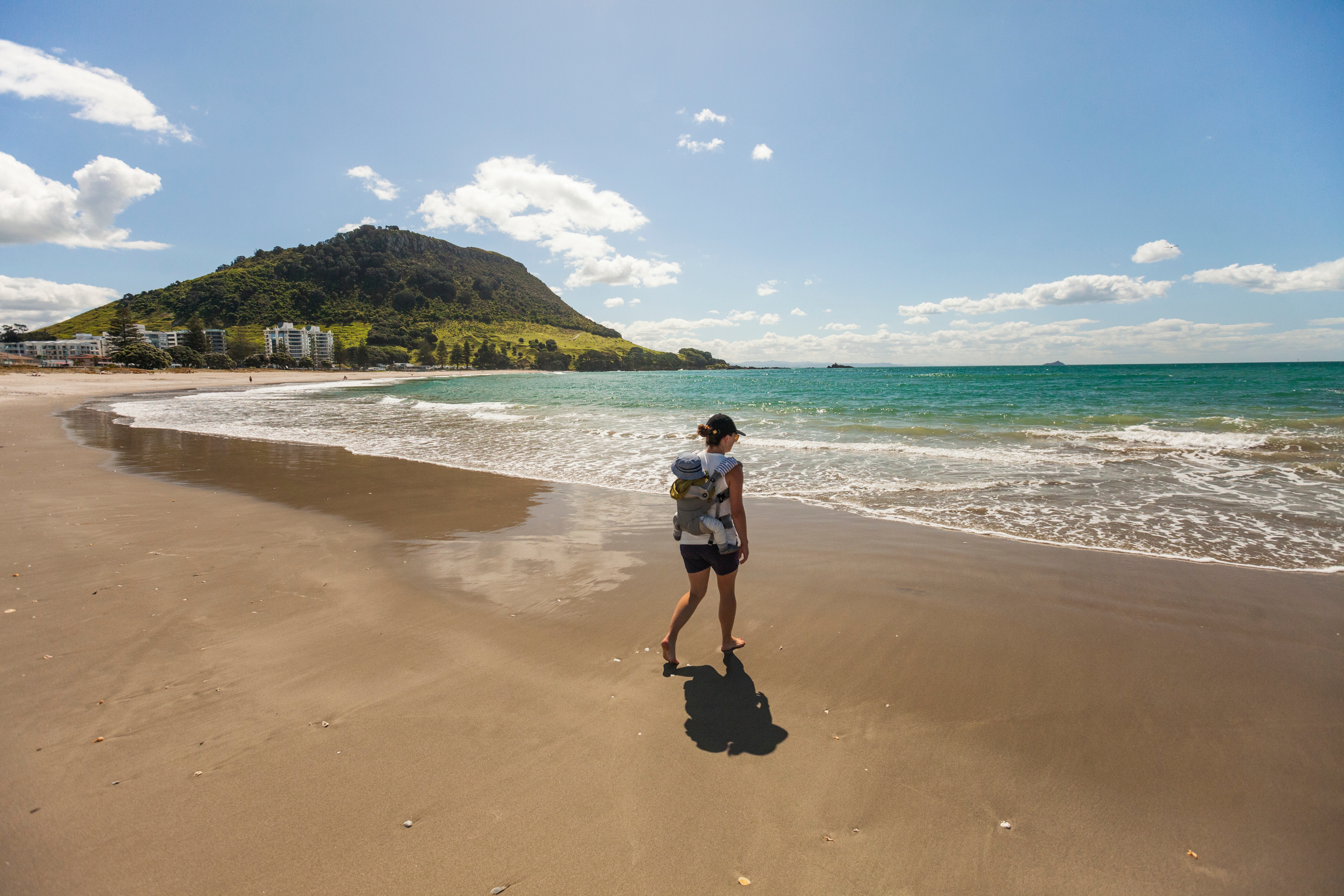 Women and baby walking on Mount Maunganui beach in Tauranga.