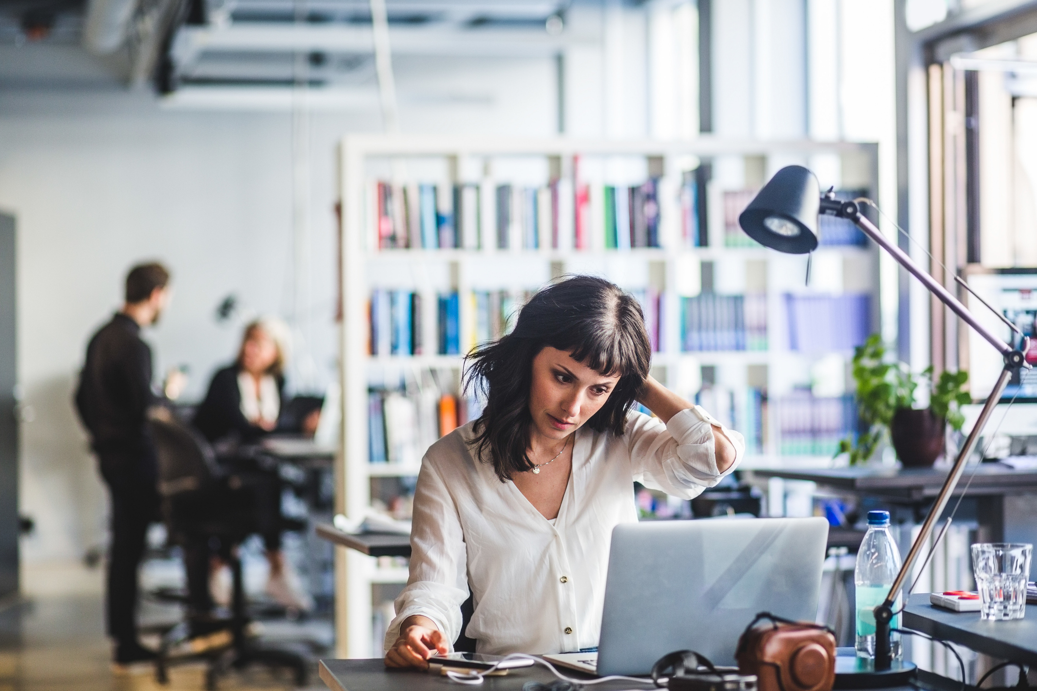 Woman at office desk scratching her head