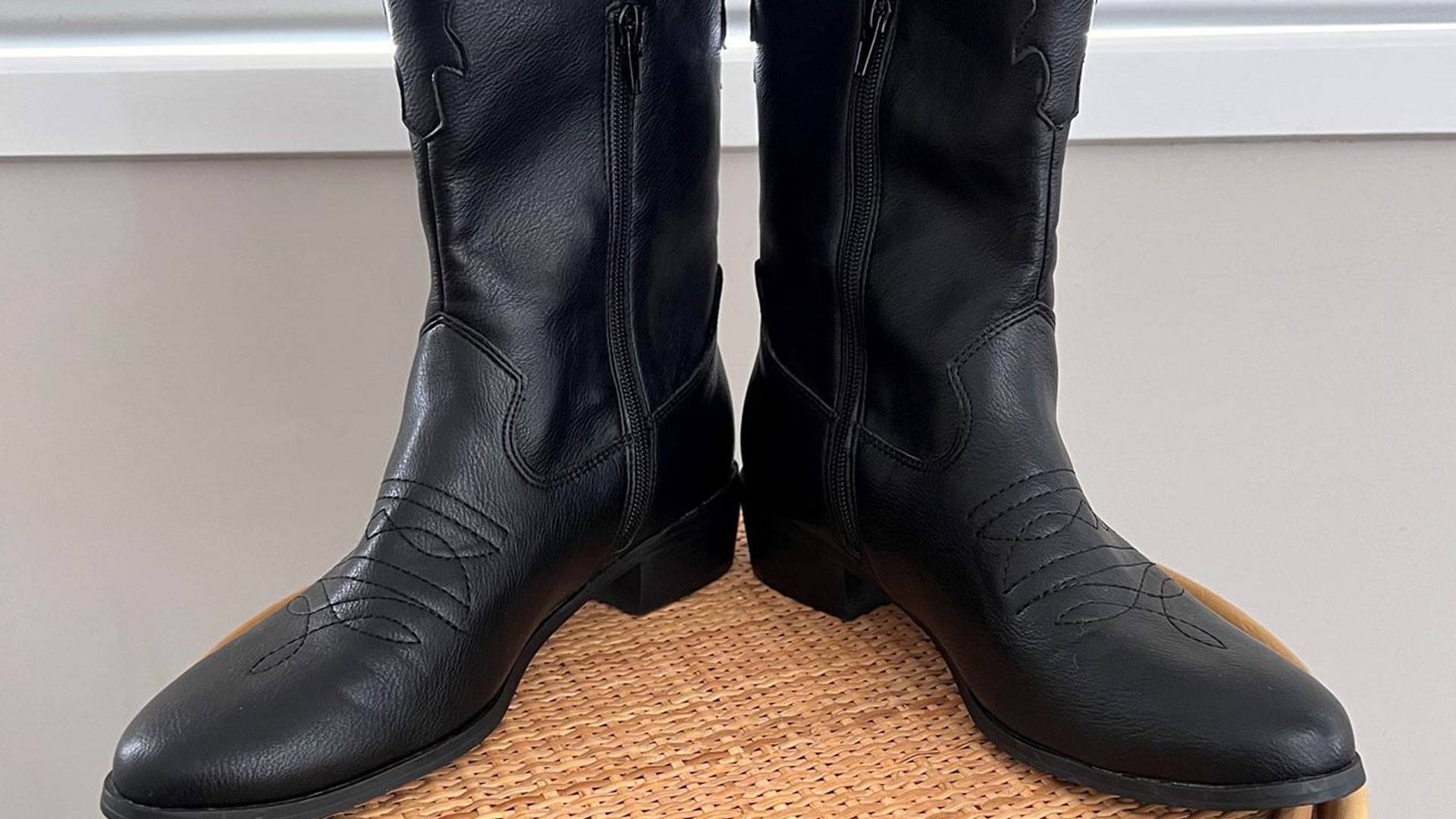 A pair of black knee high cowboy boots.