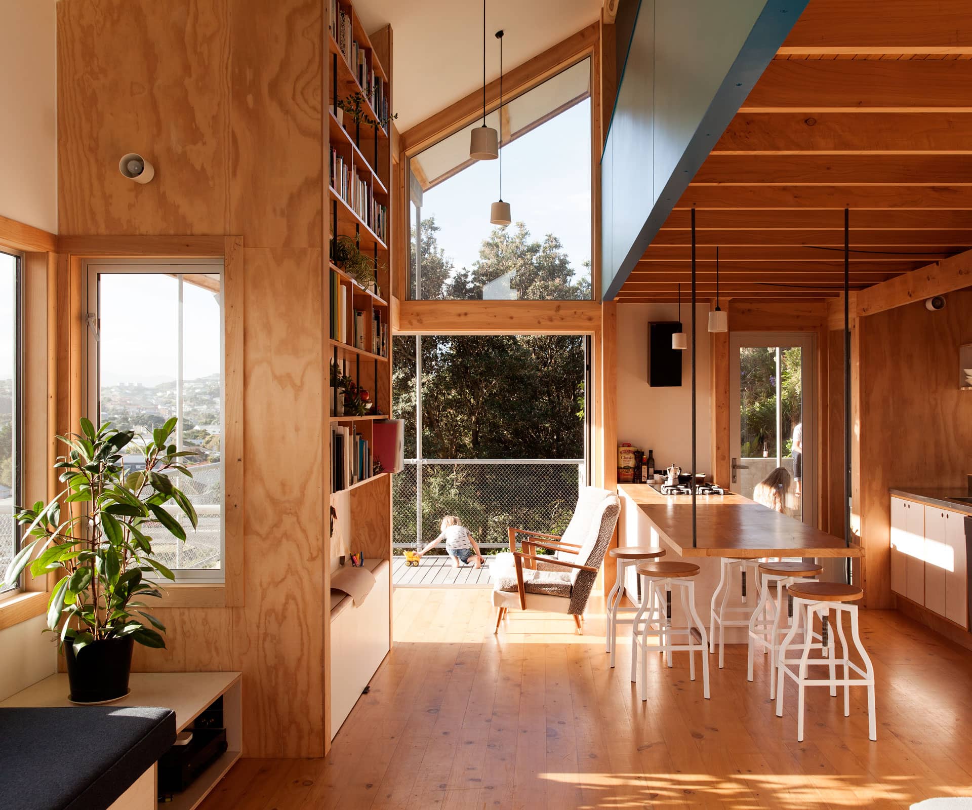 The key is that everything does double duty: the bench in the open kitchen is hung from the rafters by steel poles and doubles as a dining table.