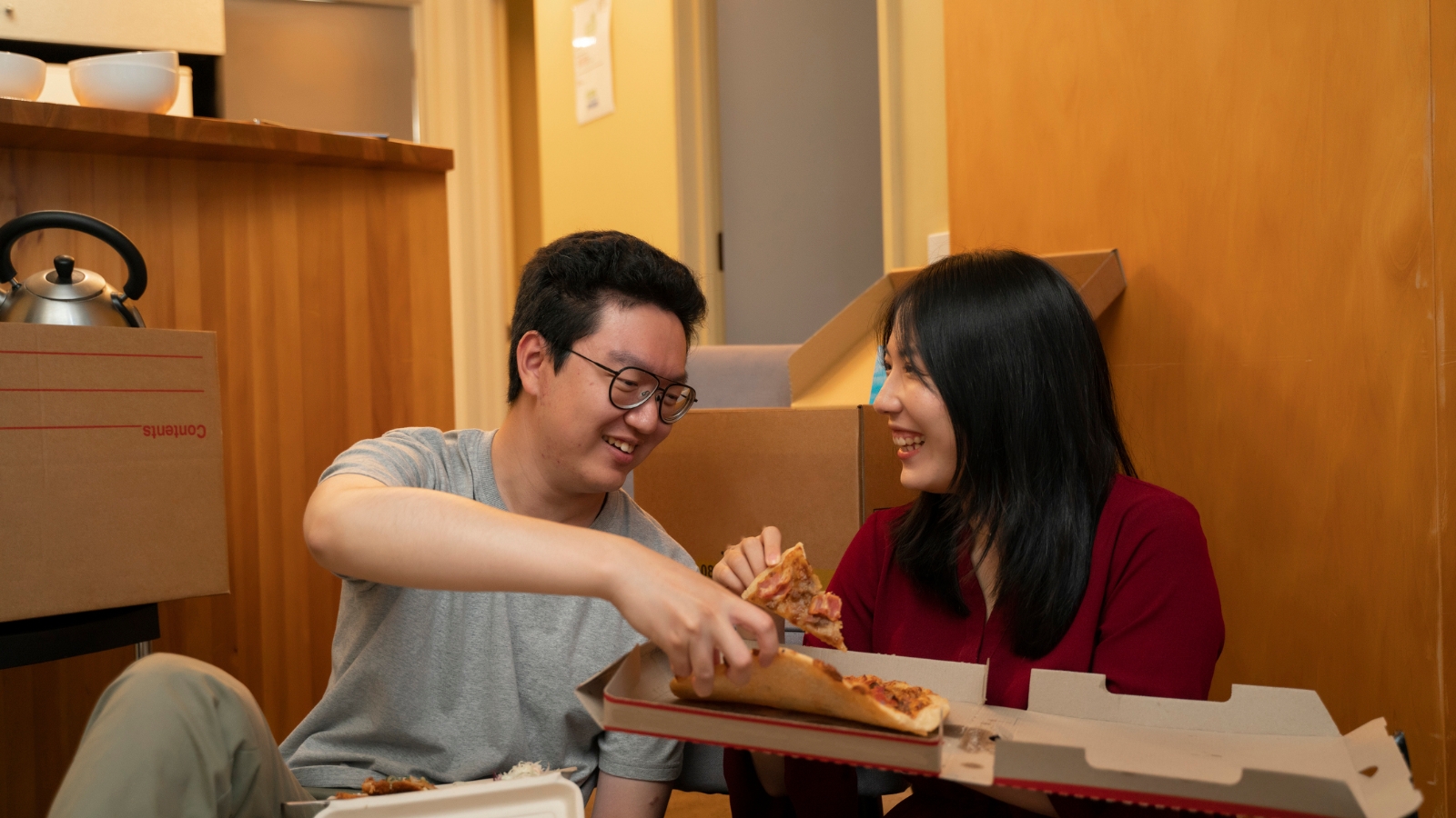 Young couple eating pizza on th floor after moving in.