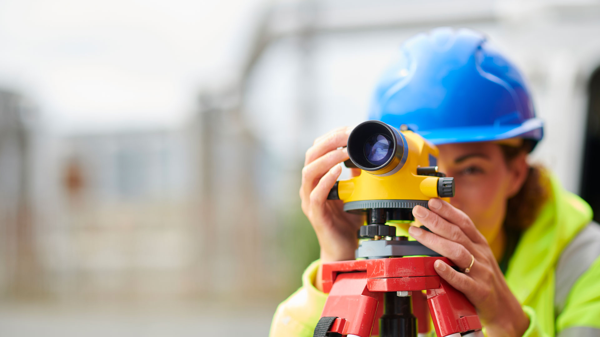 Female surveyor working on a site wearing a high vis and a hard hat.