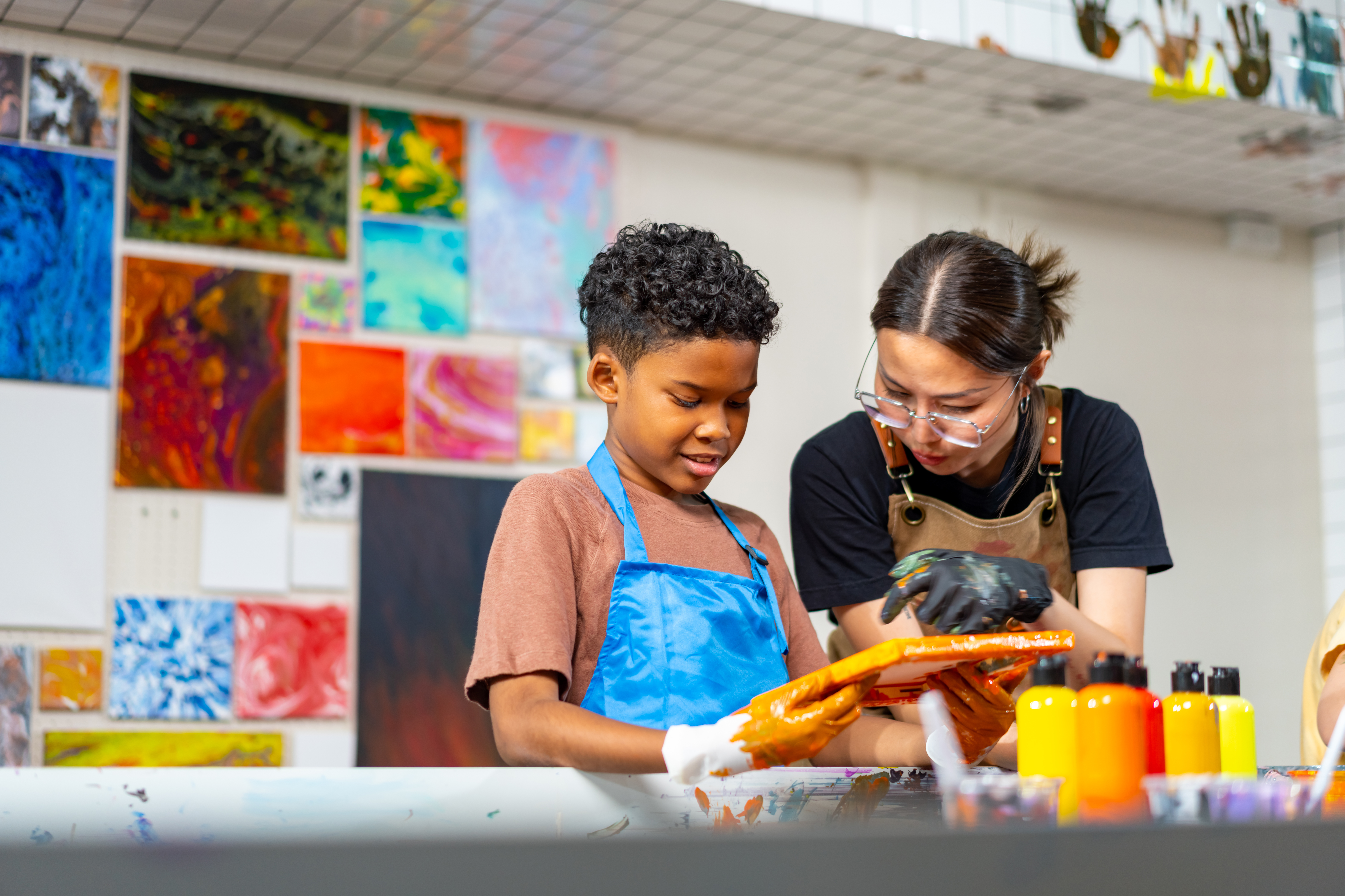 Female teacher working with young boy to do art in the classroom