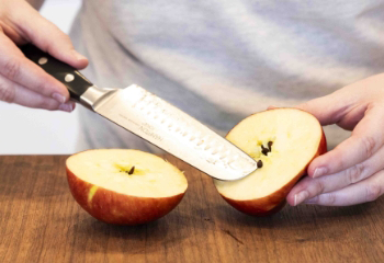 A person holding one half of the apple while the other half is on the table face up