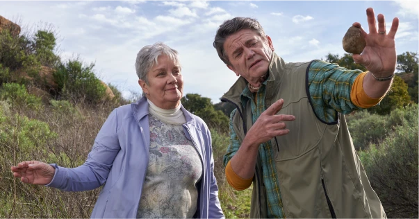 Older woman and man standing outside looking at a rock