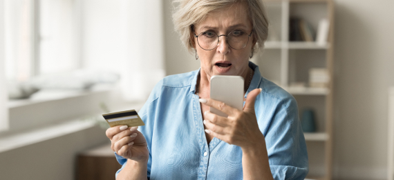 Older woman with credit card and phone looking concerned