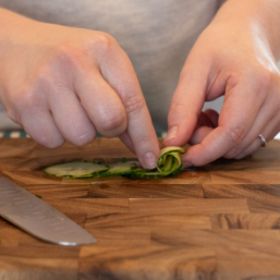 Hands rolling the peeling of the cucumber into a petal shape