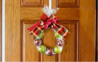 edible wreath made of red and green apples hanging on wood door