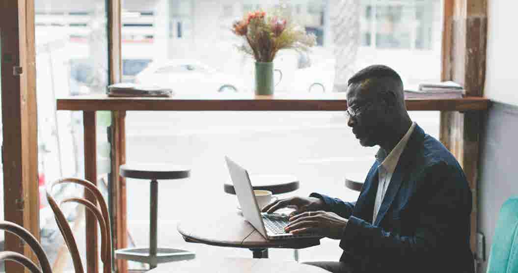 Gentleman using his laptop in a café to research online lending reviews