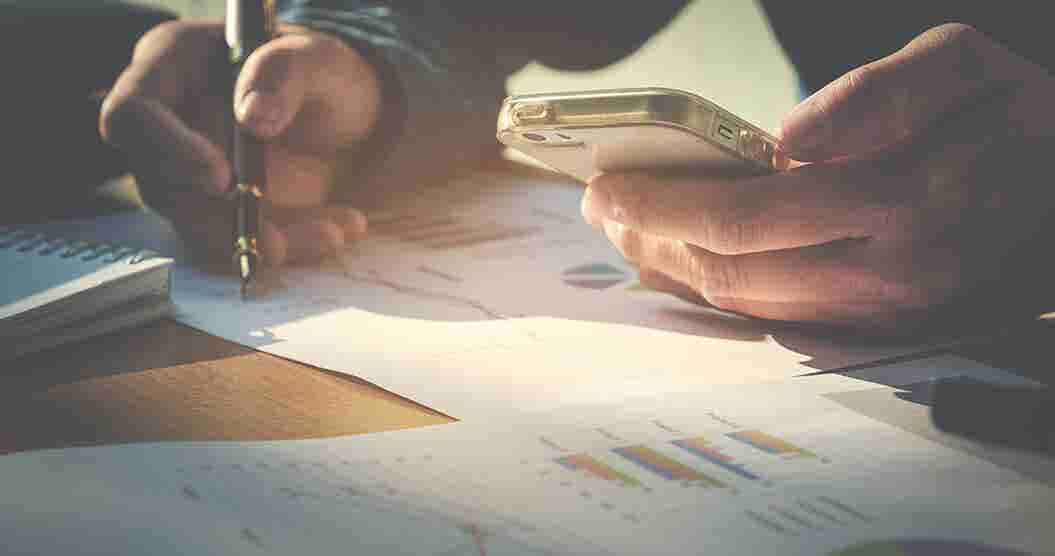 Person at desk holding calculator and writing