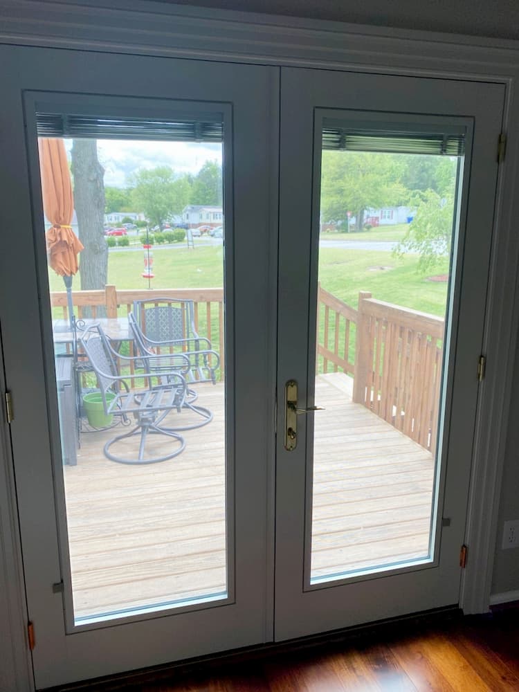 Interior view of white wood double hinged French patio door leading to balcony