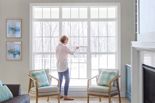 Woman opening up white windows in living room