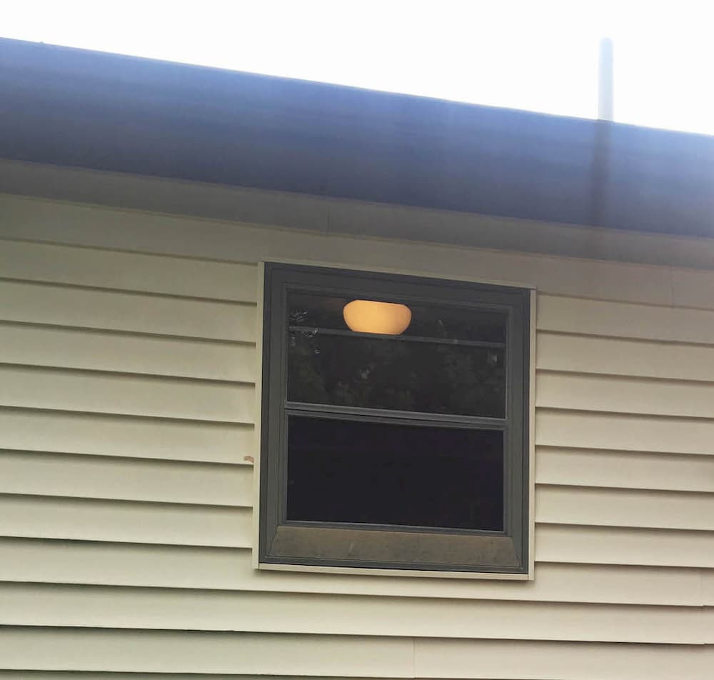 Old double-hung window on home with beige siding