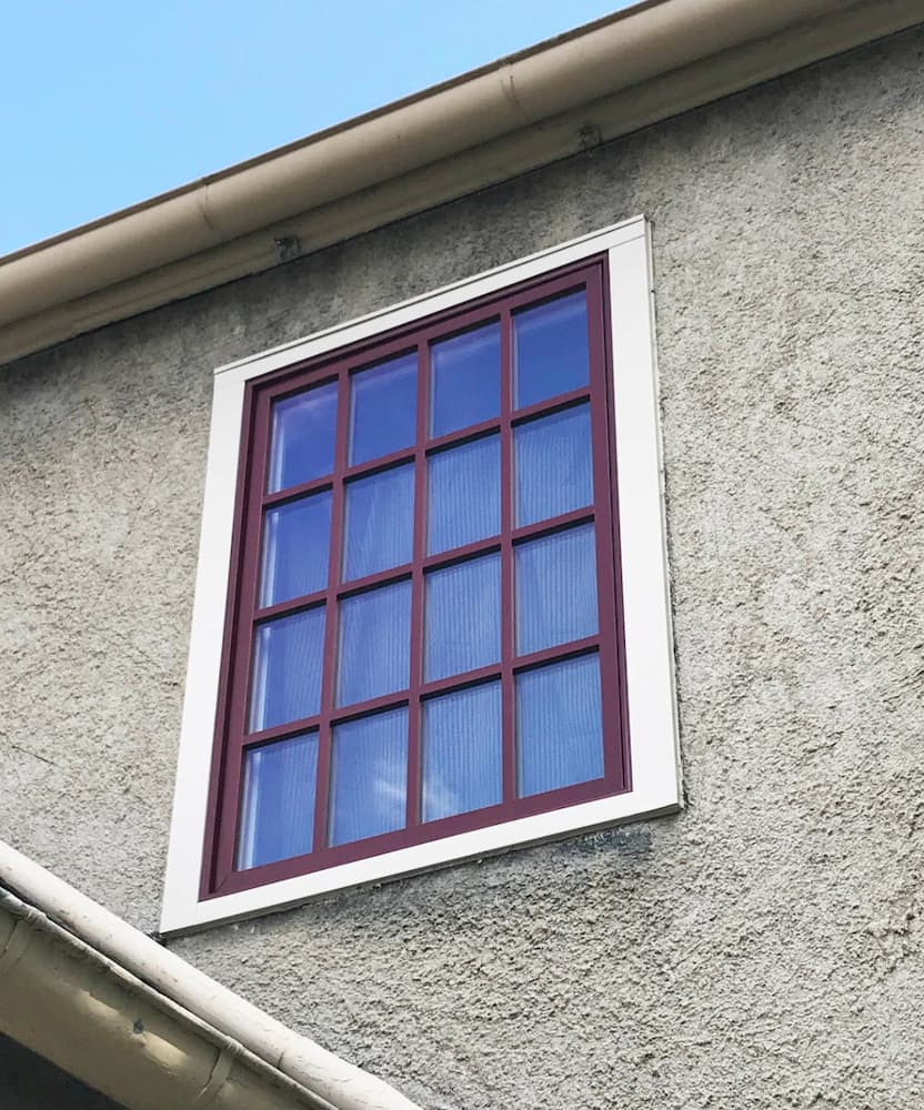 Exterior view of new wood window with red finish and traditional grille profile