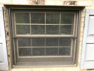 Exterior view of old brown double-hung window with screen