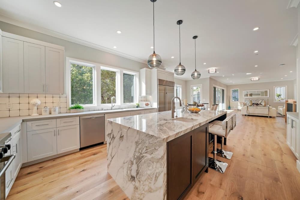 Spacious kitchen with three white wood casement windows over the sink area