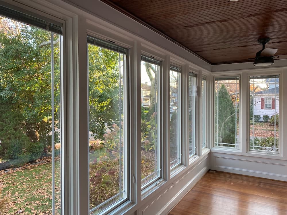 Interior view of white, casement wood sunroom windows, which overlook the yard
