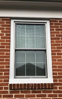 Exterior view of white wood double-hung window on a brick home