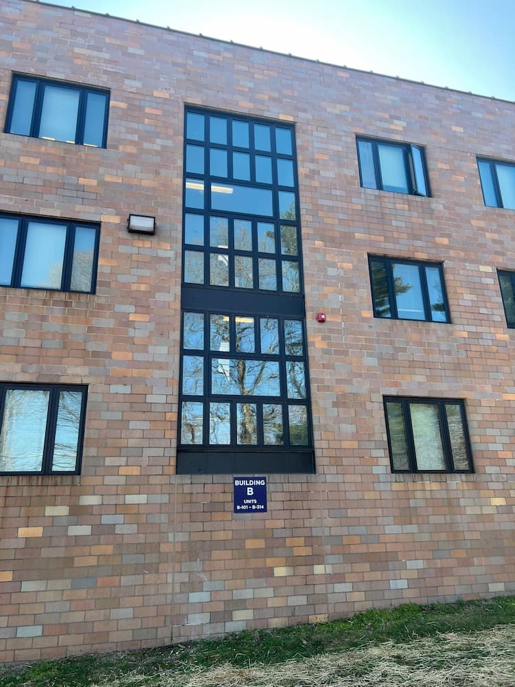 Close-up of varying black fiberglass window styles on a historic brick apartment building