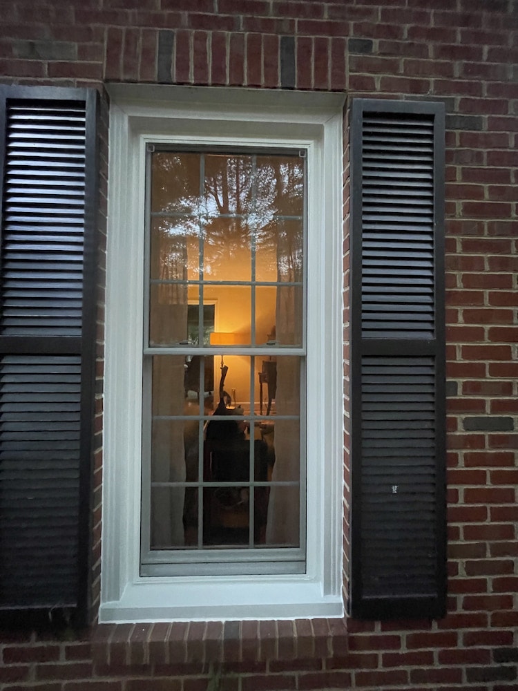 Close-up of Charlottesville home exterior with white double-hung window and black shutters