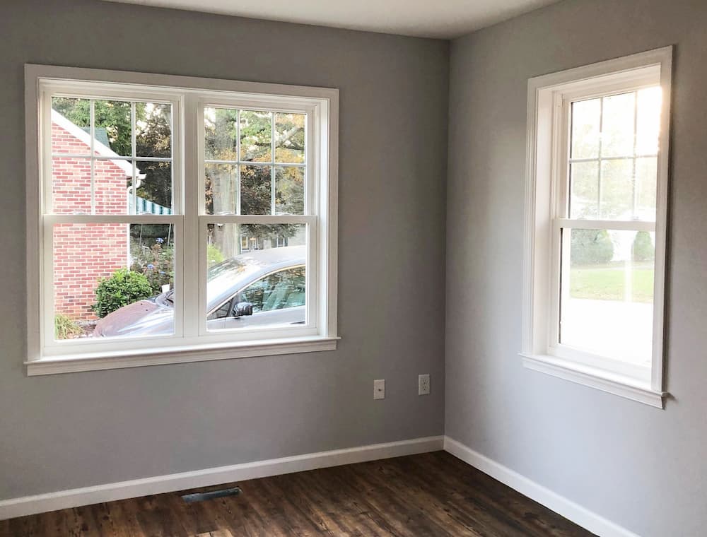 Interior view of a corner of a room with gray walls and new white vinyl double-hung windows