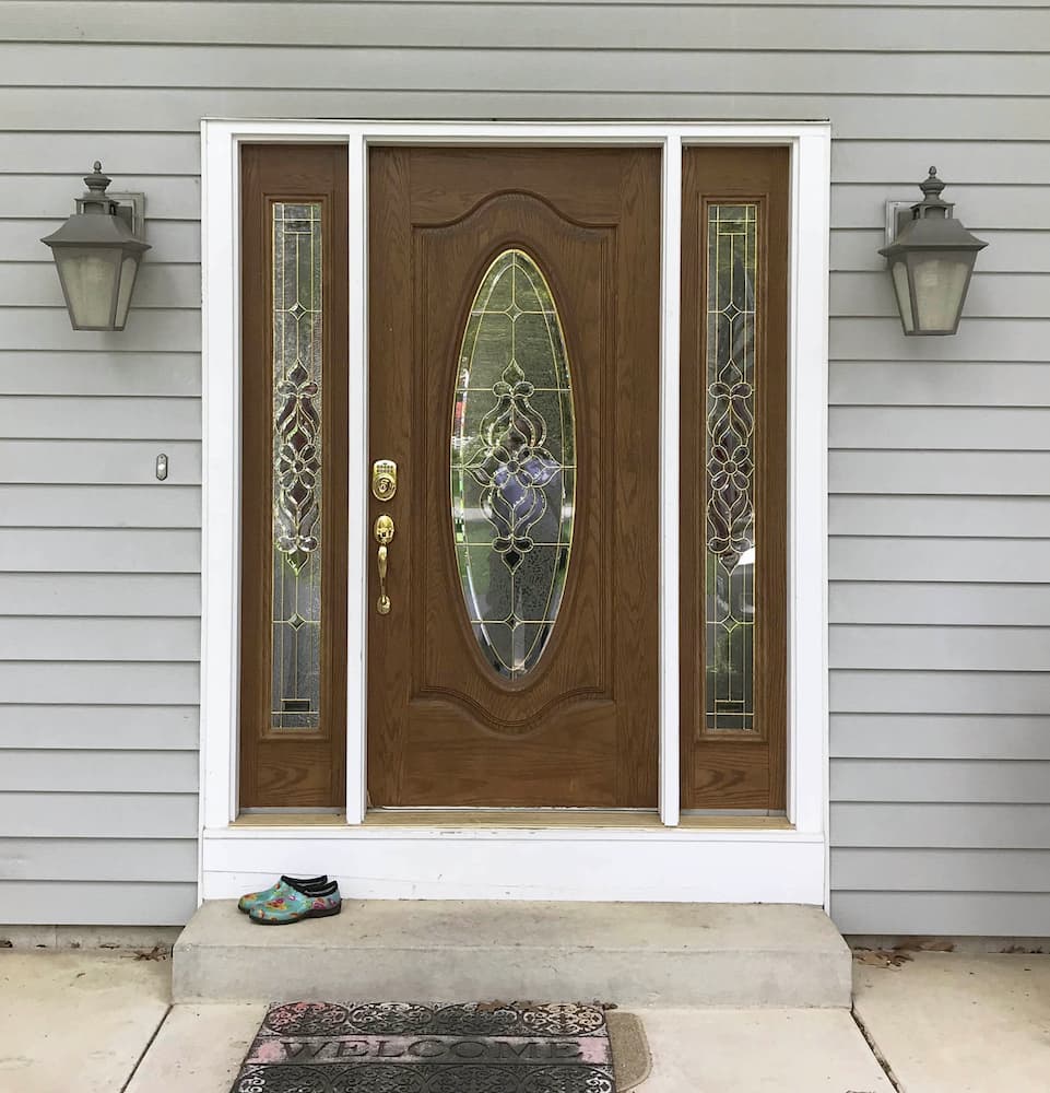 Old wood-look entry door with twin sidelights and decorative glass