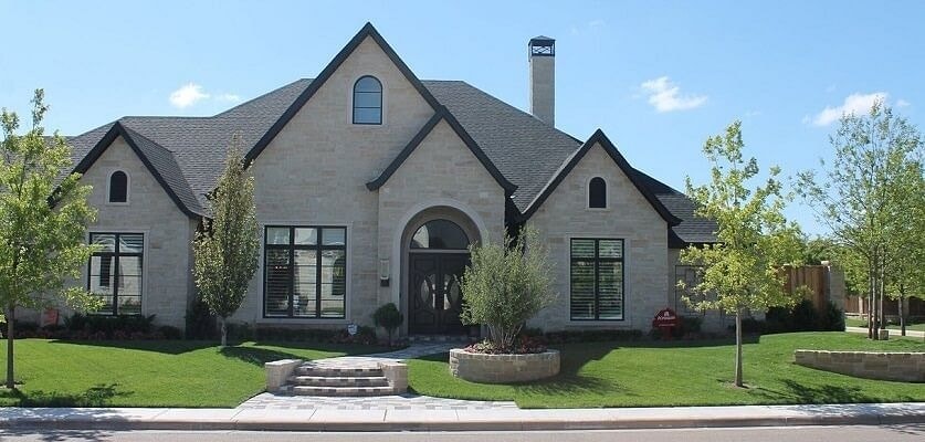 Stone home with arched entryway and landscaping