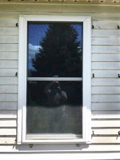 Old double-hung window on home with white siding