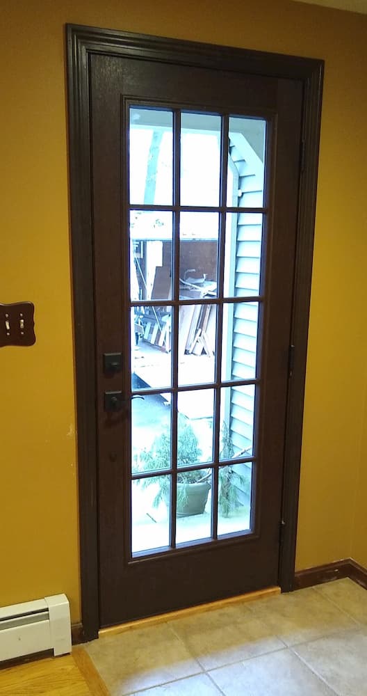 Interior view of new wood entry door with traditional grille pattern on glass