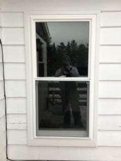 Exterior view of white vinyl double-hung window against white siding