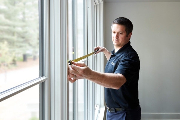 Pella window expert measuring windows with a tape measure