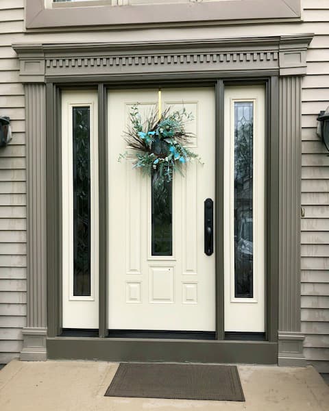 New cream-colored fiberglass entry door framed by two full-length sidelights with statement glass