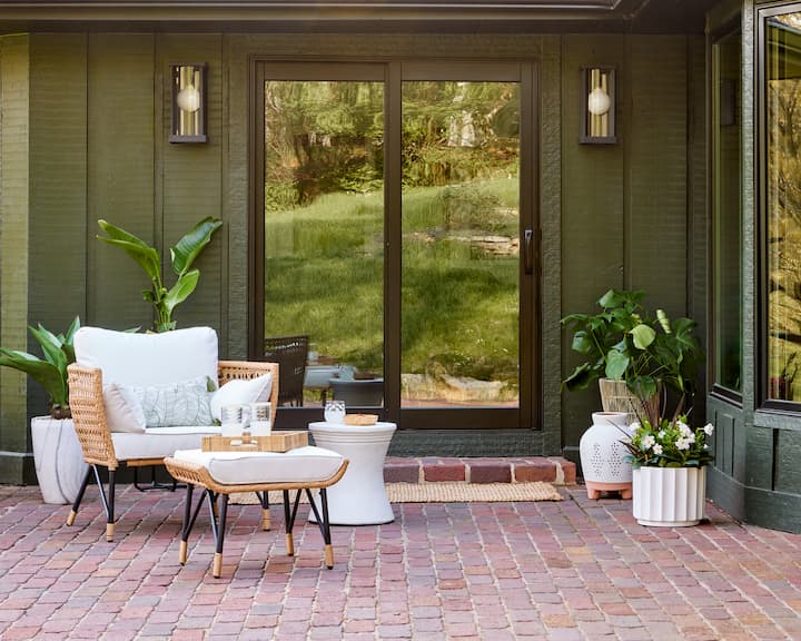 Black sliding patio door with back patio set up with chair, table, and plants