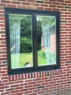 New black wood casement windows on red brick home