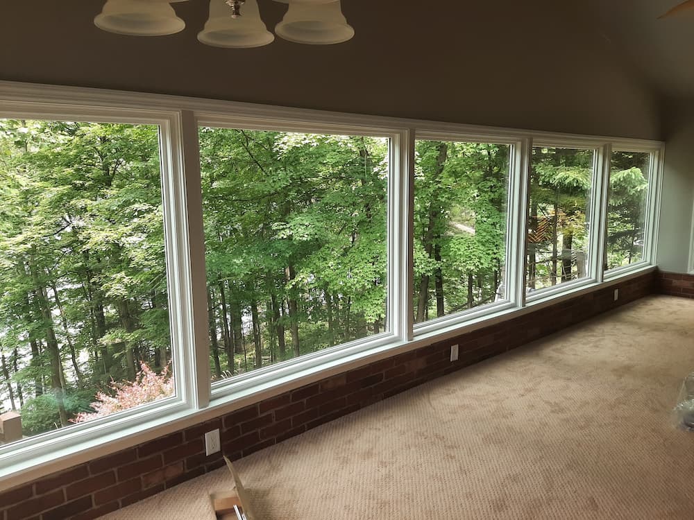 Row of white large picture windows overlooking Pittsburgh home's view of forest