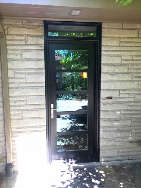 Back fiberglass entry door with contemporary grille pattern and a transom window