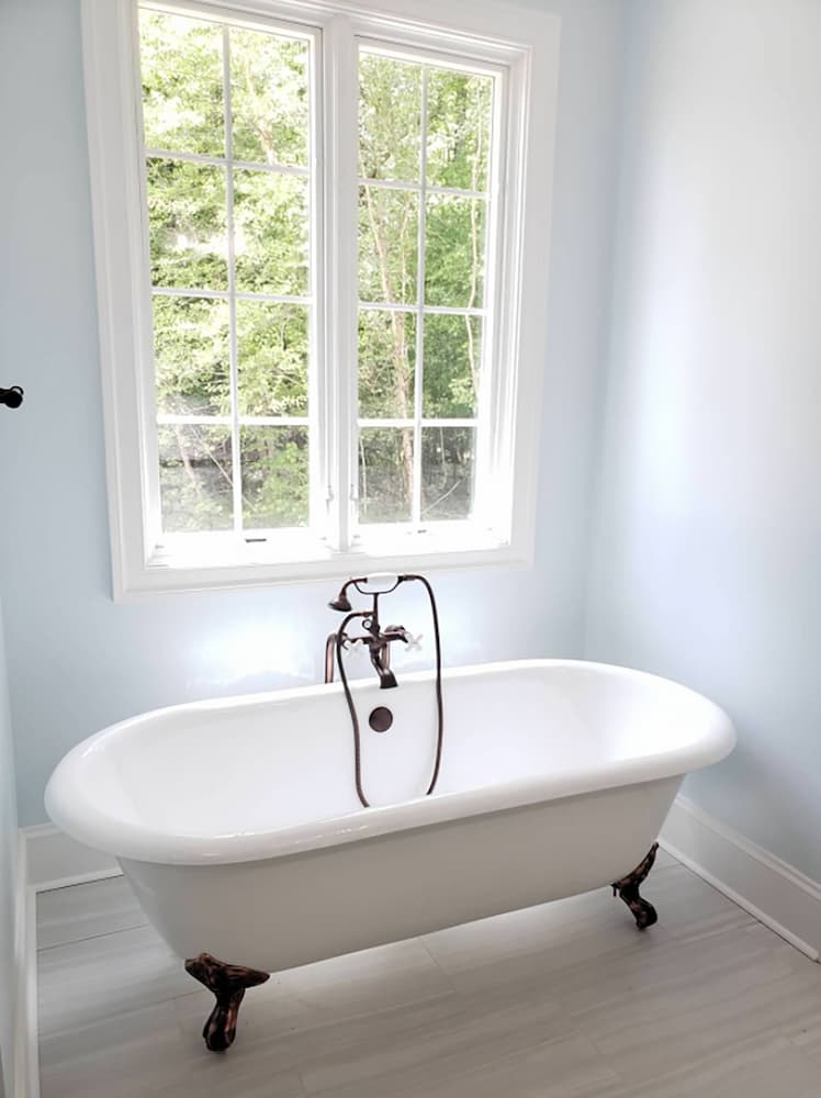 Free-standing bathtub positioned in front of new wood double-hung windows in New Kent