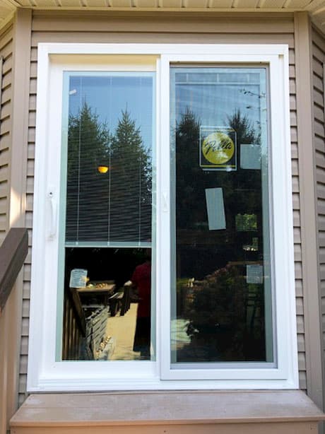 White vinyl sliding patio door on a home with beige siding