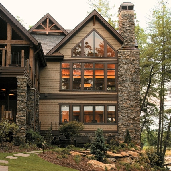 A traditional home with a large chimney and beautiful prairie windows