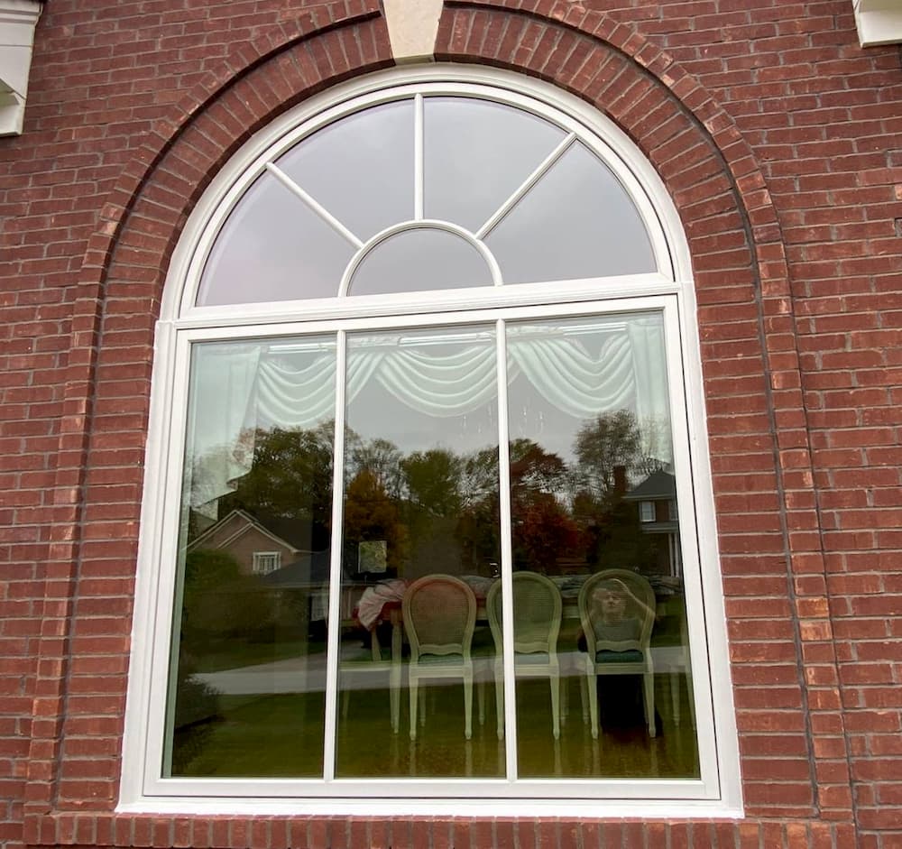 Exterior view of red brick home with new fixed wood window with half circle transom