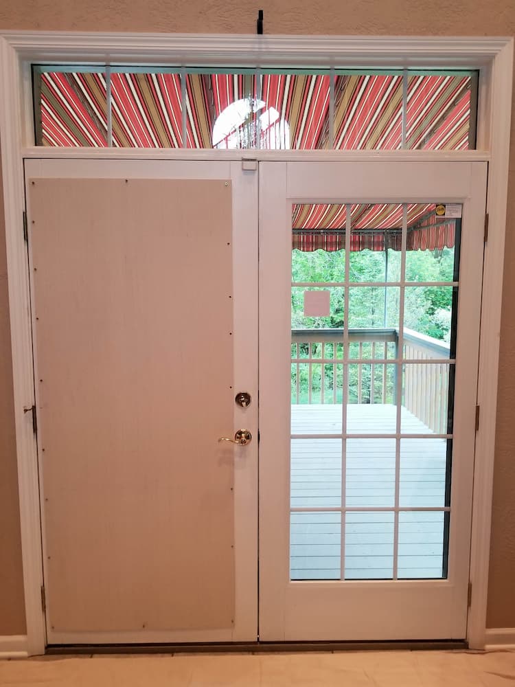 Interior view of old hinged patio door with plywood