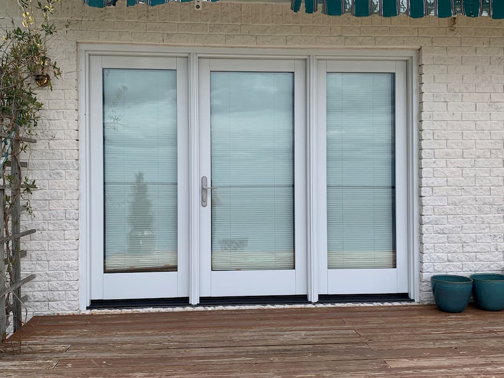 Three-panel hinged French patio door replacement with white trim