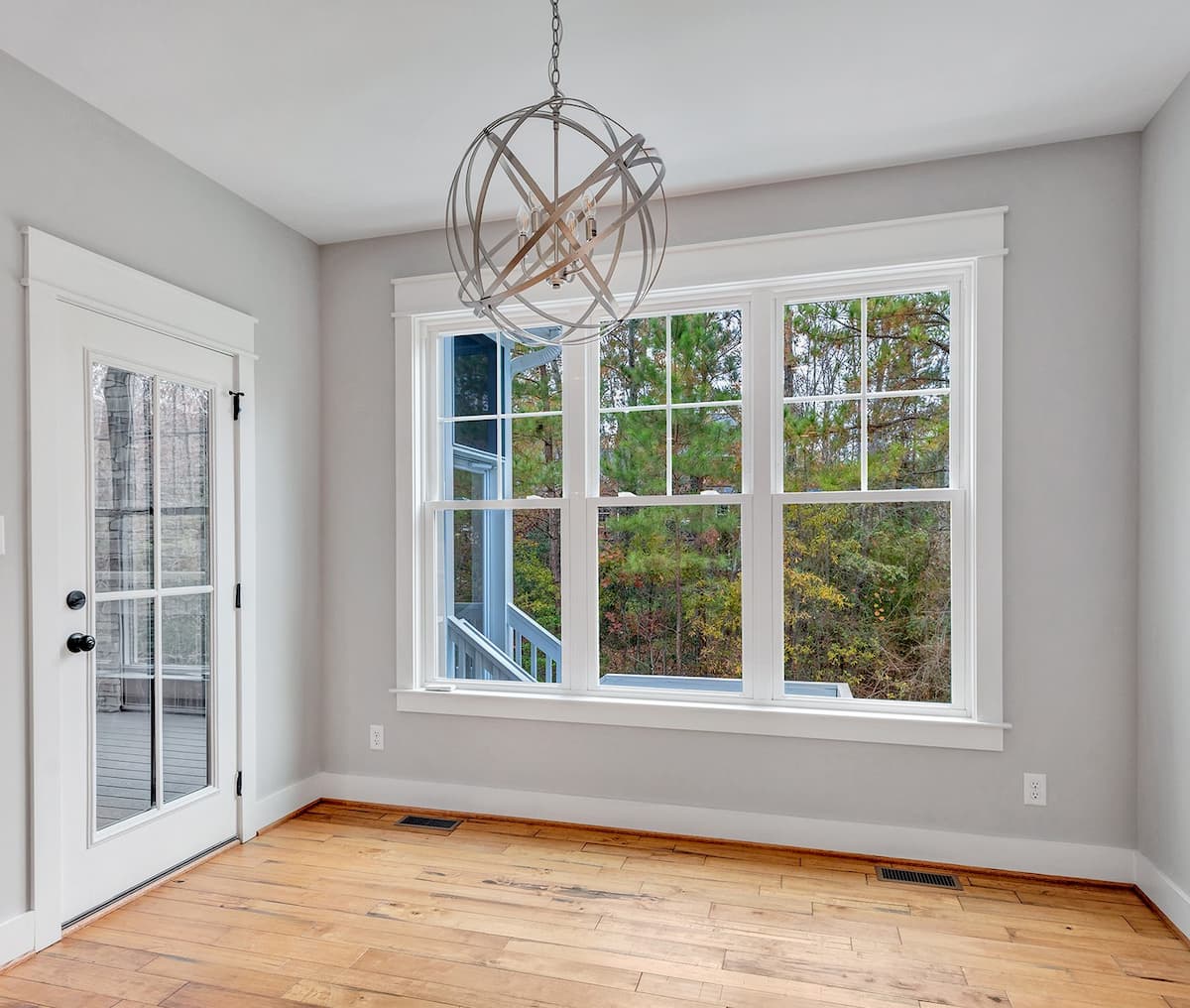 gray room with three white vinyl double-hung windows, a chandelier, and a white door