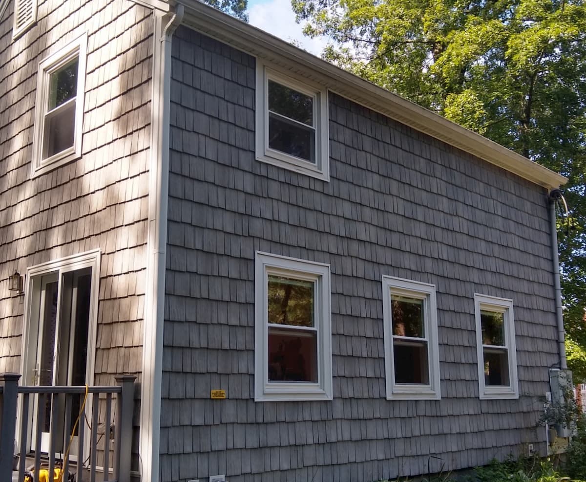 Exterior side view of shingle-style home with new energy-efficient vinyl windows