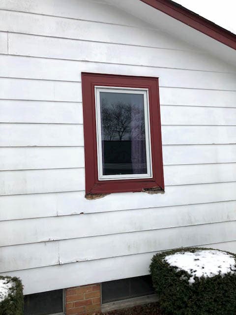 Damaged wood window on home with white siding