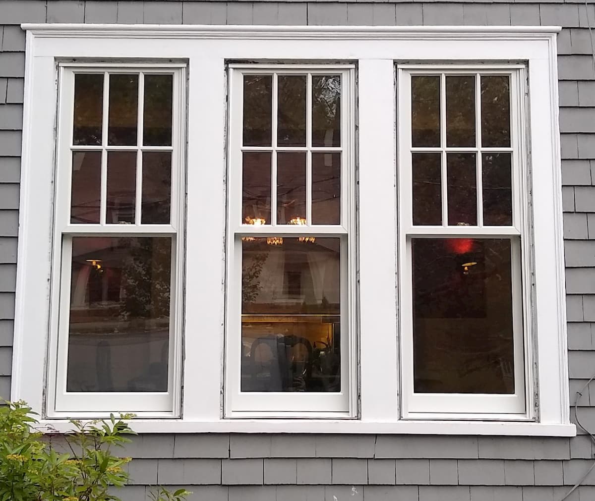 Exterior view of three white wood double-hung windows.