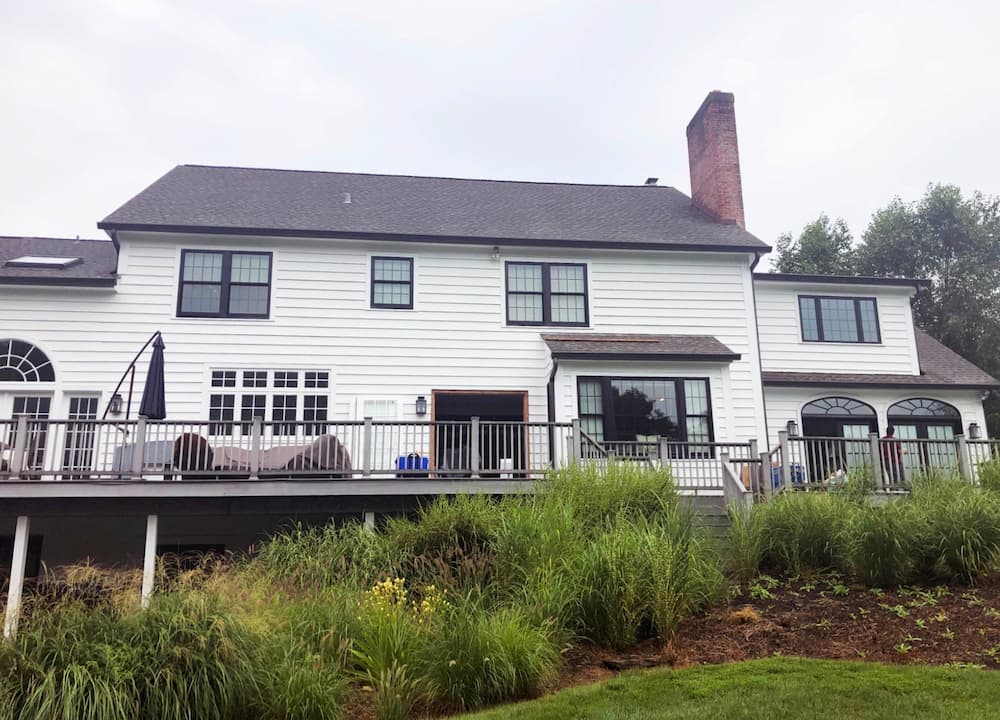 Rear exterior view of white colonial home with black windows