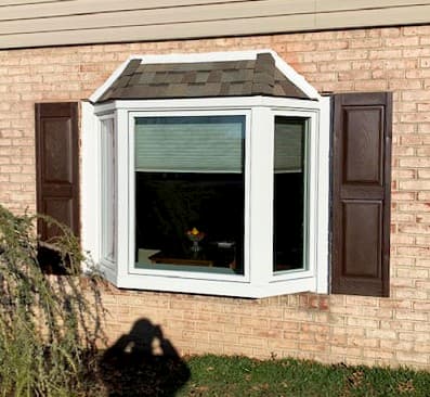 Exterior view of new white wood bay window on a brick home
